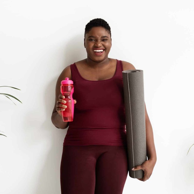Happy black woman plus size with bottle of water