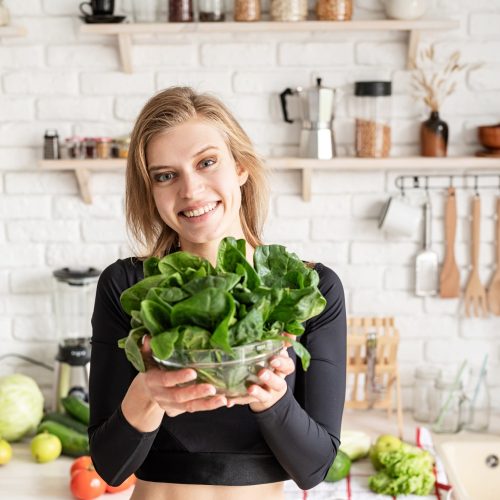healthy-eating-diet-and-cooking-concept-young-blond-smiling-woman-holding-a-bowl-of-fresh-spinach.jpg