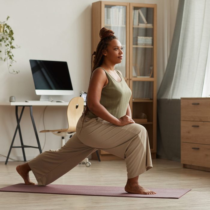 Woman exercising on exercise mat she stretching her legs during sports training at home